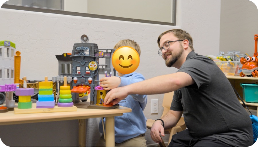 Therapist and child playing with a toy garage at a table