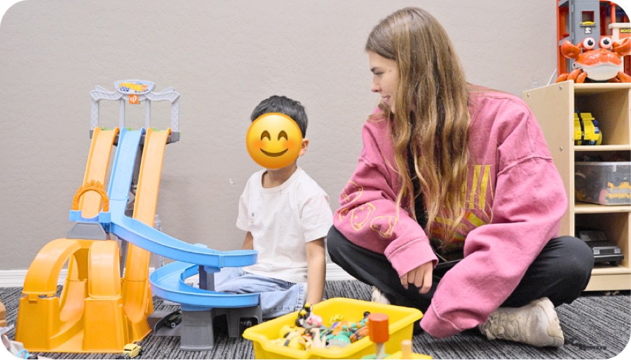 Therapist and child playing with a race track together